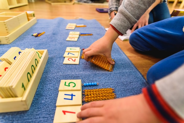Mains d'un élève utilisant des matériaux en bois dans une école montessori. Photo Premium