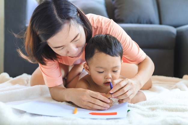 Maman Asiatique Apprend A Son Mignon Petit Garcon A Utiliser Des Crayons De Couleur Pour Dessiner Sur Papier A La Maison Concept De Famille Et De Convivialite Photo Premium