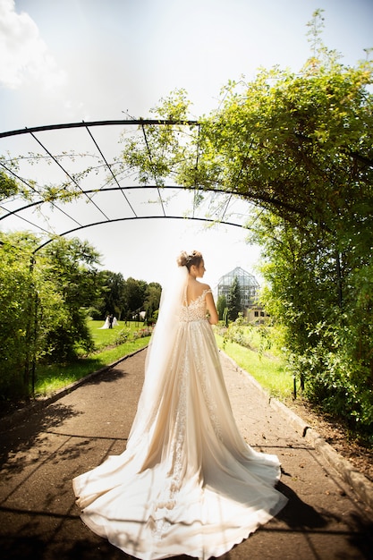 Mariée en robe de mariée de mode sur fond naturel. un beau portrait de femme dans le parc. vue arrière Photo Premium