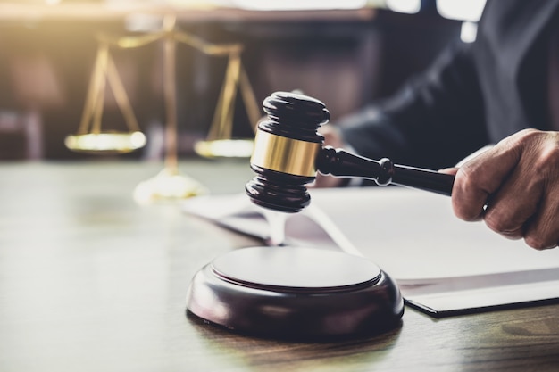Marteau sur une table en bois et avocat ou avocat travaillant sur des documents. droit juridique Photo Premium
