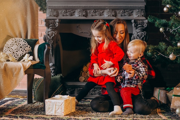 Mère avec enfants par sapin de noël Photo gratuit