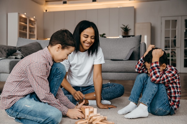 Une Mere De Famille Noire Heureuse Et Deux Fils Palying Un Tour De Jenga Photo Premium