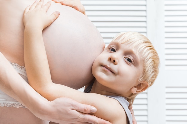 La Mere De La Femme Enceinte Et Le Bebe Sont Enlaces Un Garcon Mignon Pencha Son Oreille Contre Le Ventre De Sa Maman Photo Premium