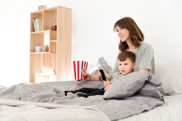 Mère Et Fils Au Lit Devant La Télé Photo Gratuite