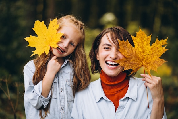 Mère avec sa petite fille dans la forêt pleine de feuilles d'or Photo gratuit