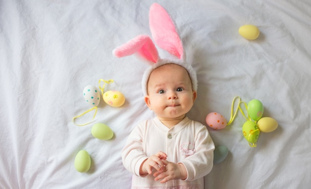 Mignon Bebe Drole Avec Des Oreilles De Lapin Et Des Oeufs De Paques Colores A La Maison Sur Fond Blanc Photo Premium