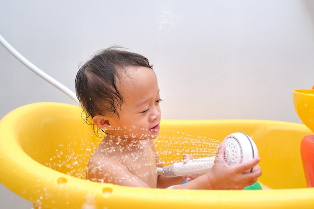 Mignon Petit Bebe Asiatique 1 An Bebe Fille Enfant S Amusant Assis Dans La Baignoire Tenant Une Douche Dans Sa Main Photo Premium