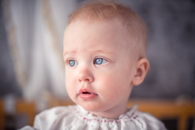 Mignon Petit Bebe Aux Cheveux Blonds Et Aux Yeux Bleus Est A Cote De Gros Plan Photo Premium