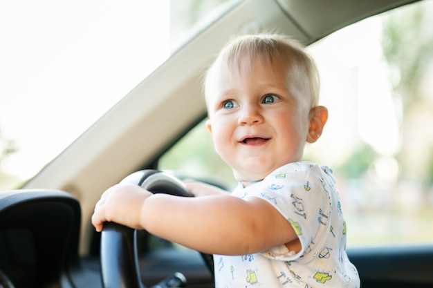 Mignon Petit Bebe Garcon Conduisant Une Grosse Voiture Tenant Le Volant Souriant Et Impatient Avec Interet Photo Premium