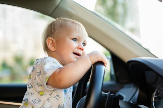 Mignon Petit Bebe Garcon Conduisant Une Grosse Voiture Tenant Le Volant Souriant Et Impatient Avec Interet Photo Premium