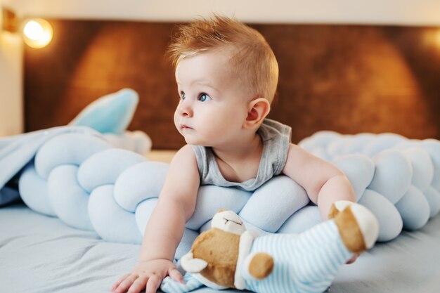 Mignon Petit Bebe Garcon Couche Sur Le Ventre Sur Med Jouant Avec L Ours En Peluche Et En Detournant Les Yeux Photo Premium