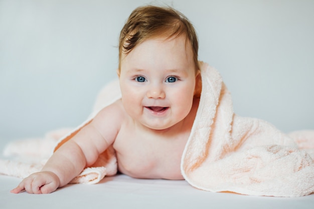 Mignon Petit Bebe Souriant Recouvert De Serviette De Bain Allonge Sur Le Ventre Apres Le Bain Photo Premium