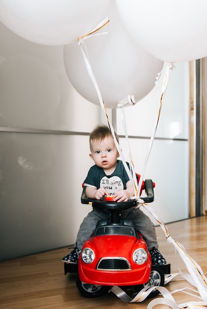Mignon Petit Garcon Assis Dans Une Voiture Rouge Avec De Gros Ballons Blancs Enfance Heureuse Jeux Pour Enfants Bebe Photo Premium
