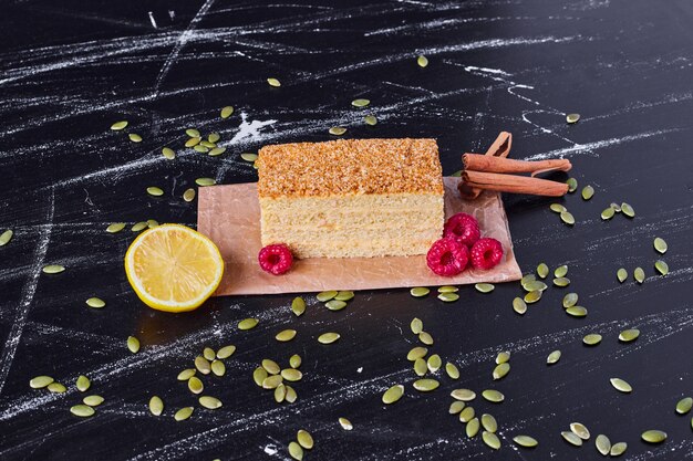 Un Morceau De Gateau Au Miel Avec Des Baies Et De La Cannelle Sur Une Table En Marbre Photo Gratuite