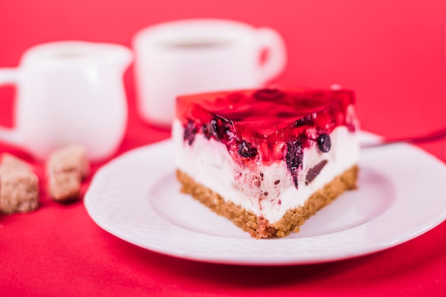 Un Morceau De Gateau Aux Fraises Sur Une Plaque Blanche Sur Fond Rouge Photo Gratuite