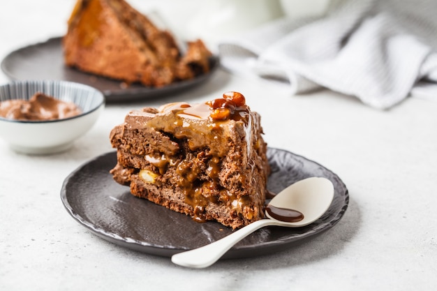 Morceau De Gateau De Snickers Fait Maison Avec Creme Au Chocolat Et Caramel Sur Une Soucoupe Noire Fond Blanc Photo Premium