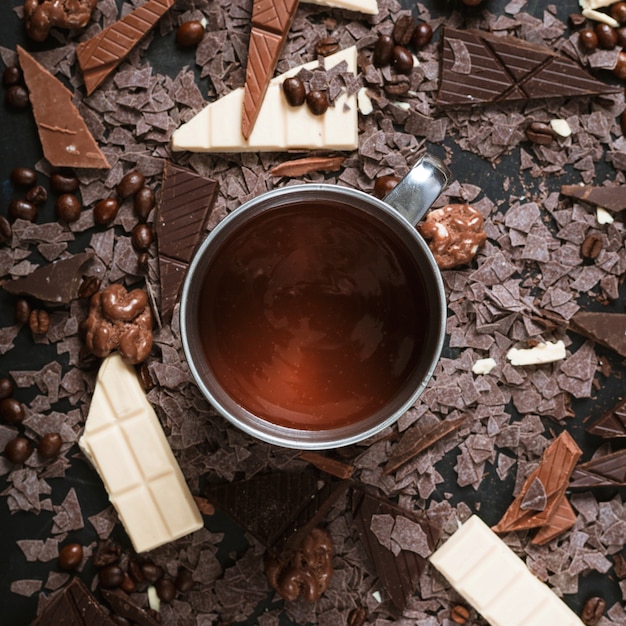 Morceaux de chocolat avec des grains de café torréfiés; noix et chocolat fondu dans une tasse Photo gratuit