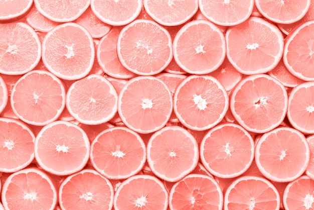 Motif créatif. texture de fruits orange en tranches fraîches. macro, vue de dessus avec espace de copie. cadre de la nourriture. oranges juteuses sur fond de couleur corail. Photo Premium