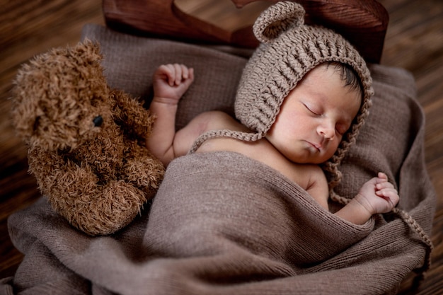 Nouveau Ne Beau Bebe Se Trouve Et Tenant Un Petit Ours En Peluche Dans Le Lit Sur Bois Photo Premium