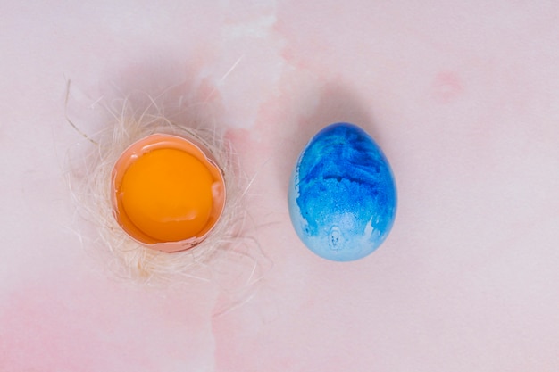 Oeuf de pâques bleu avec oeuf cassé au nid Photo gratuit