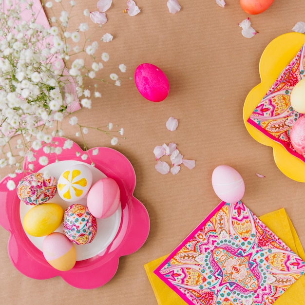 Oeufs de pâques sur une assiette près des serviettes et des fleurs Photo gratuit