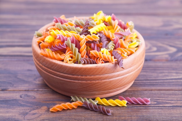 Pâtes fusilli aux épinards, carottes, betteraves dans un bol en bois sur une table sombre Photo Premium