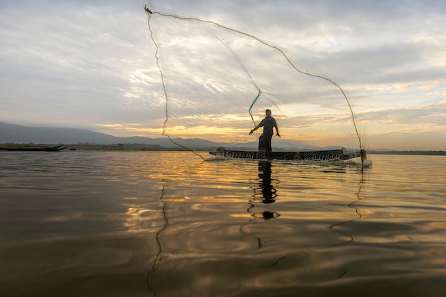 Les pêcheurs qui pêchent commencent à pêcher tôt le matin avec des bateaux en bois, de vieilles lanternes et des filets. style de vie du pêcheur. Photo Premium