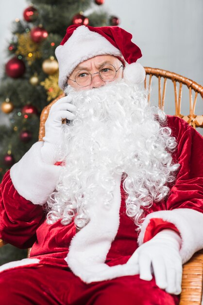 Père Noël Assis Sur Une Chaise à Bascule Et Parler Par Téléphone