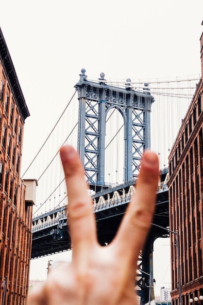 Personne montrant le signe de la paix sur fond de pont Photo gratuit