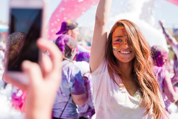 Une personne prenant selfie de son amie souriante sur téléphone mobile pendant holi Photo gratuit