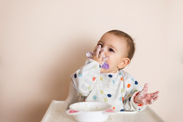 Un Petit Bebe En Train De Manger Son Diner Et De Faire Des Degats Avec Du Yaourt Et Des Cereales Photo Premium