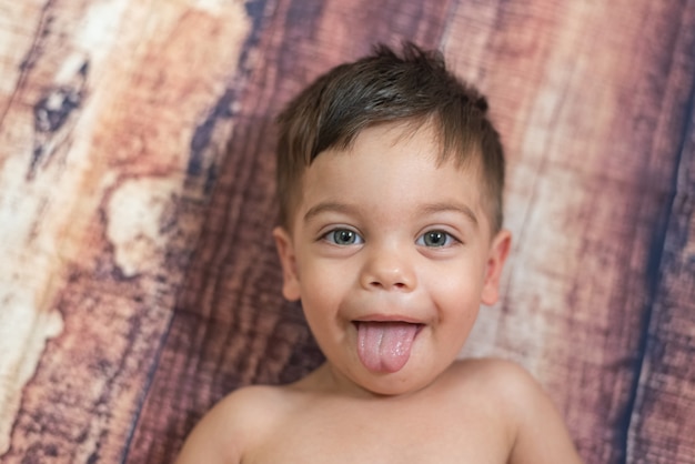 Petit Garcon Aux Yeux Bleus Allonge Sur Un Fond En Bois Avec La Langue Trainer Photo Gratuite