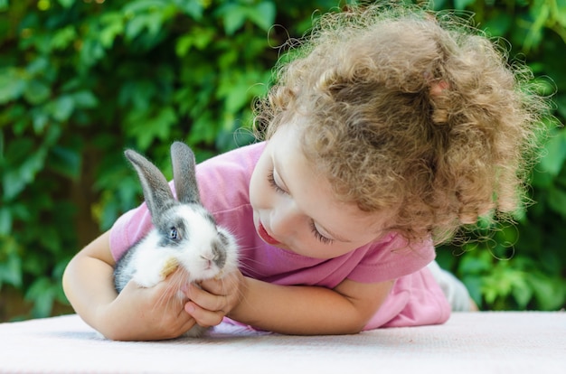 Petite Belle Fille Souriante Serrant Un Bebe Lapin Sur Le Vert En Ete Heureux Enfant Riant Et Animal De Compagnie Jouant A L Exterieur Lapin Est Un Symbole De Paques Photo Premium