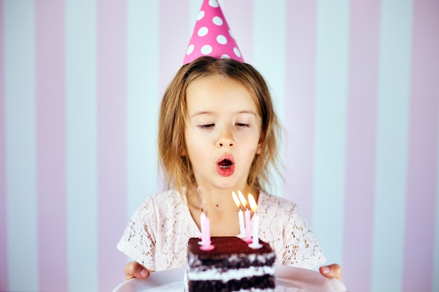 Petite Fille Au Chapeau Rose Soufflant Des Bougies Sur Un Gateau Au Chocolat D Anniversaire Sur Sa Fete D Anniversaire A La Maison Portrait Anniversaire Enfant Photo Premium