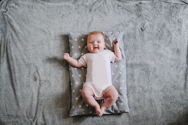 Petite Fille Bebe Se Trouve Sur Un Oreiller Gris Chaud Un Plaid Un Bebe Allonge Sur La Surface D Une Couverture Douce Tient Le Jouet Et Sourit Mise A Plat Vue De Dessus