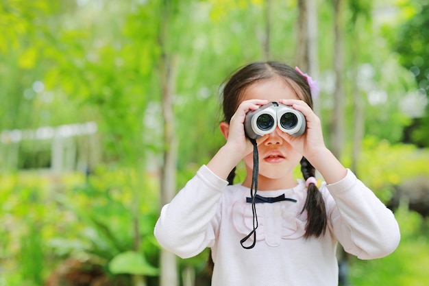 Petite Fille Enfant Dans Un Champ A La Recherche A Travers Des Jumelles Dans La Nature En Plein Air Photo Premium