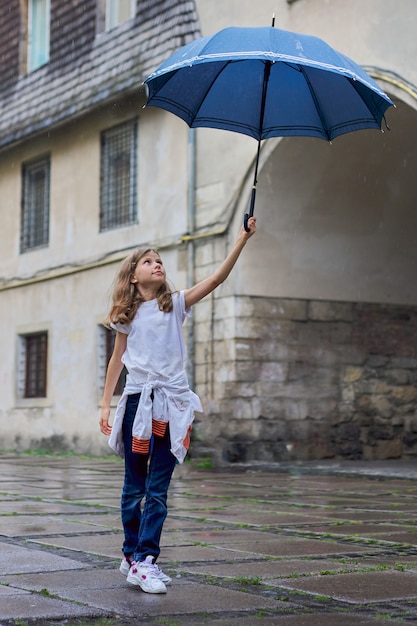 Petite Fille Enfant Sous La Pluie Avec Un Parapluie Fond De Vieille Ville Touristique Photo Premium