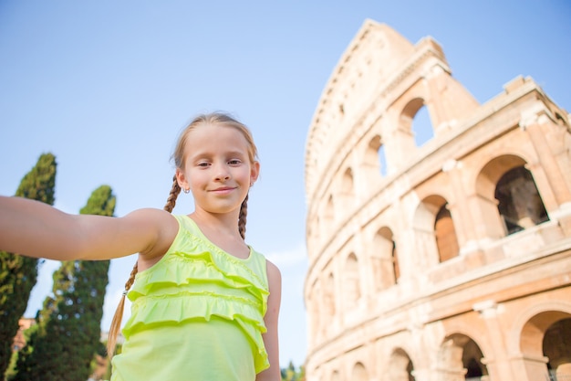 Petite fille faisant selfie fond colisée, rome, italie. portrait d'enfant dans des lieux célèbres d'europe Photo Premium