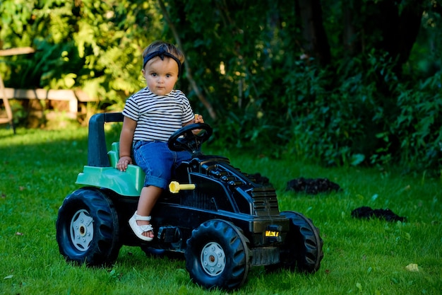 Petite Fille Jouant Avec Un Tracteur Jouet Dans Un Jardin Photo Premium