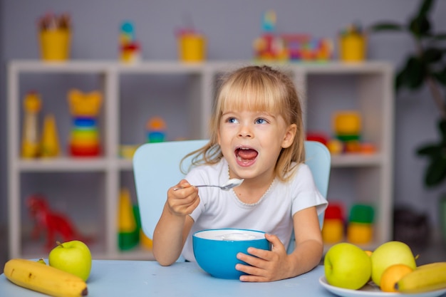 Petite Fille Mange Du Porridge Ou Du Fromage Cottage Pour Le Petit Dejeuner Photo Premium