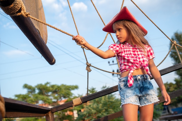 Petite Fille Pirate Dans Une Chemise A Carreaux Et Un Short En Jean S Accroche Aux Cordons Du Navire Photo Premium