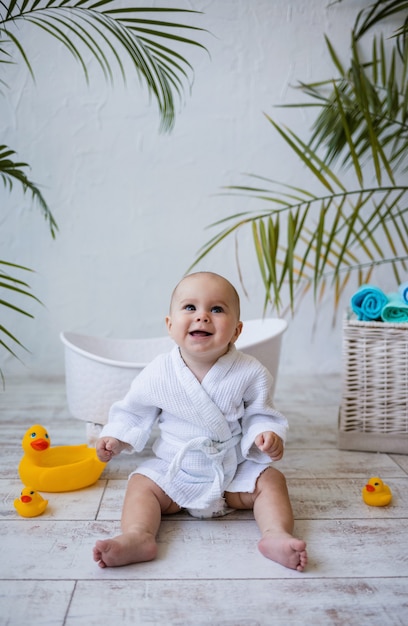 Une Petite Fille Qui Rit En Peignoir Est Assise Pres D Une Baignoire Pour Bebe Hygiene Des Enfants Photo Premium