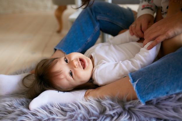 Petite fille et sa mère habillées dans un style décontracté s'amusent à jouer au sol Photo gratuit