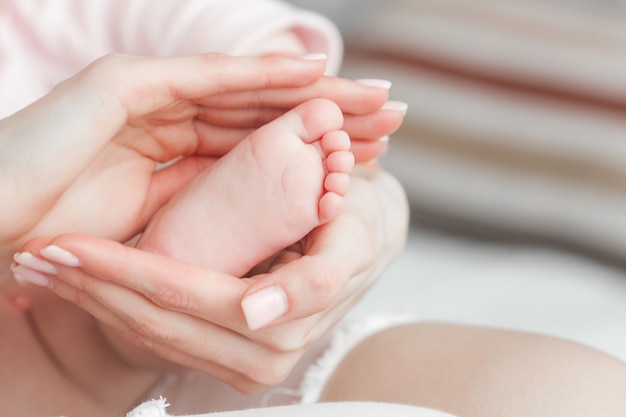 Photo Gros Plan Des Pieds De Bebe Les Mains De La Mere Tenant Le Pied De L Enfant Doigts De Petite Fille A L Avant Photo Premium