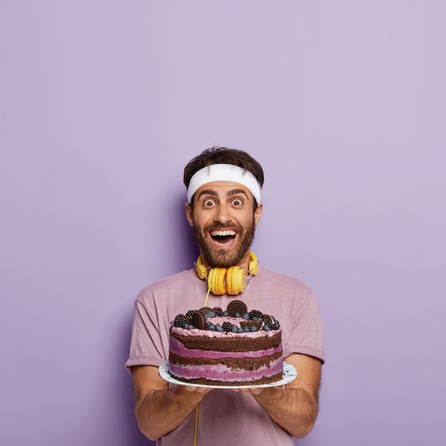 Photo D Un Sportif Heureux Ravi Tient Un Gros Gateau Aux Fruits Cuit Au Four Avec