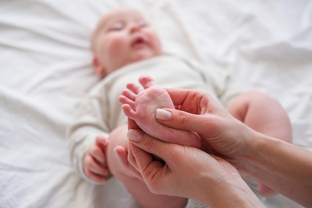 Pieds De Bebe Dans Les Mains De La Mere Jeune Femme Caucasienne Fait Massage Pour Bebe Bebe Heureux Sur Lit Blanc A La Maison Babycare Sport Et Maternite Heureuse Photo Premium