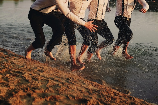 Les pieds des hommes dans l'eau. les hommes courent sur l'eau. été. groupe de heureux jeune homme pieds éclaboussures Photo Premium