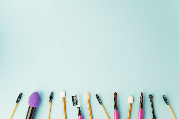 Pinceaux de maquillage professionnels et mascara disposés en rangées sur un fond coloré Photo gratuit