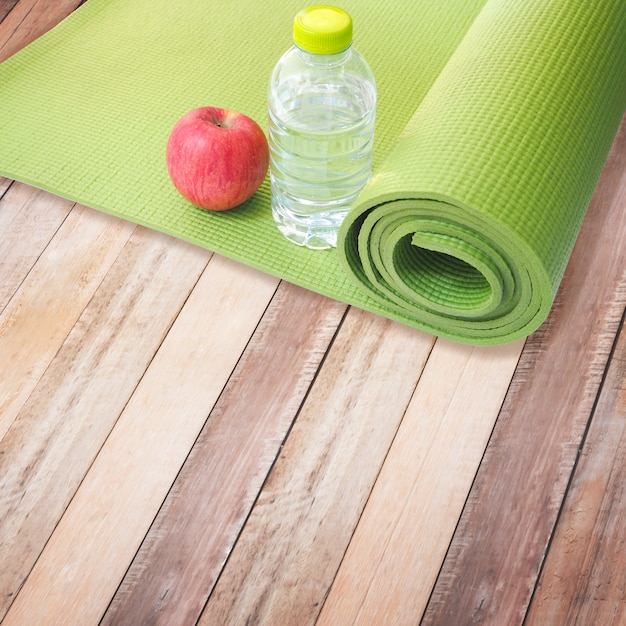 Pomme rouge, bouteille d'eau et tapis de yoga Photo Premium