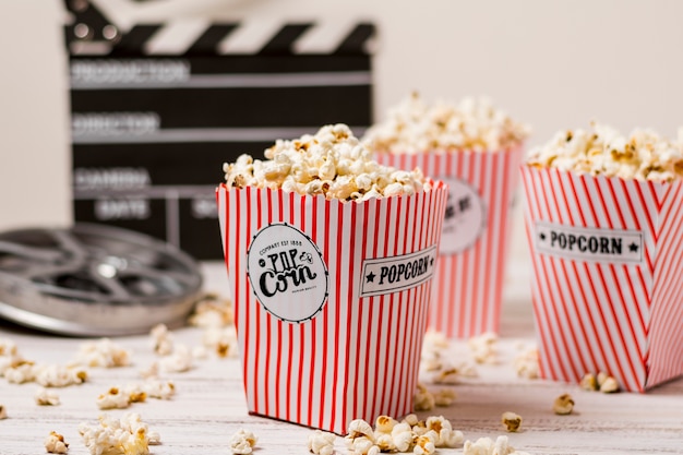 Pop-corn Dans Le Seau à Trois Rayures Avec Bobine De Film Et Clap Sur Une Planche En Bois Photo gratuit